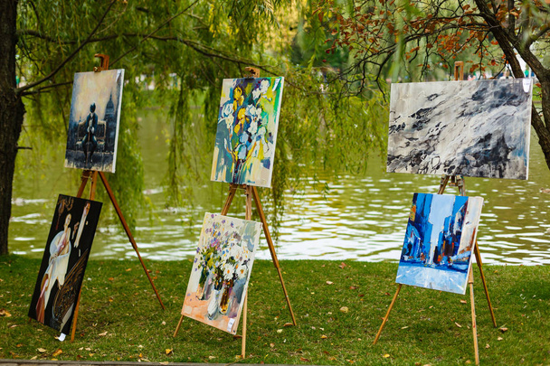 καβαλέτα με έργα ζωγραφικής σε καταπράσινο πάρκο - Φωτογραφία, εικόνα