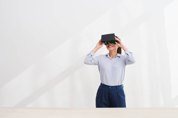 Lächelnde junge Frau mit Virtual-Reality-Brille auf dem Kopf, Virtual-Reality-Konzept  - Foto, Bild