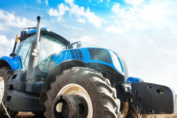 Modern tractor on a blue sky background. Concept of agricultural machinery. - Foto, Imagen