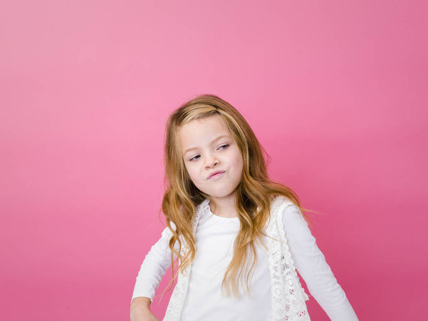 portrait of grumpy girl in casual clothes looking aside on pink background  - Фото, зображення