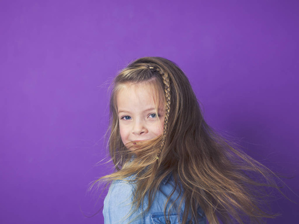 portret Ładna dziewczynka koszulkę niebieski denim przed fioletowe tło w studio - Zdjęcie, obraz