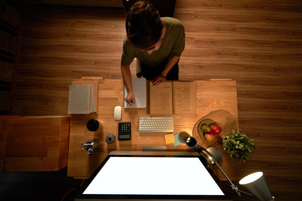 женщина сидела дома стол с компьютером записи в дневнике, вид сверху
 - Фото, изображение