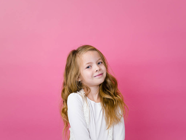portrait of happy satisfied girl in white clothes standing and looking at camera with toothy smile on pink background  - Foto, immagini
