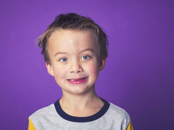happy little boy having fun while posing in front of violet background - Zdjęcie, obraz