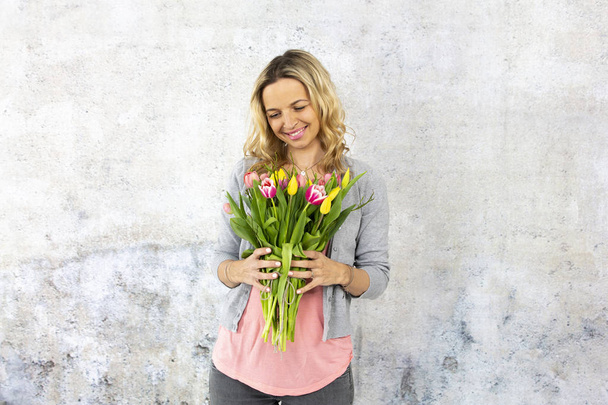 elegant woman with makeup and hairdo standing with bouquet of tulip flowers, Valentine day concept  - Foto, immagini