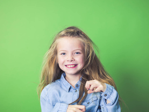 portrait of happy girl in casual clothes looking at camera on green background    - Photo, Image