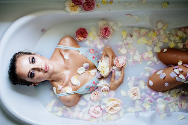 Beautiful girl in the bathroom with many flowers. - Фото, зображення