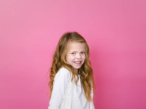 portrait of scared pretty girl in white clothes looking at camera on pink background  - Foto, immagini