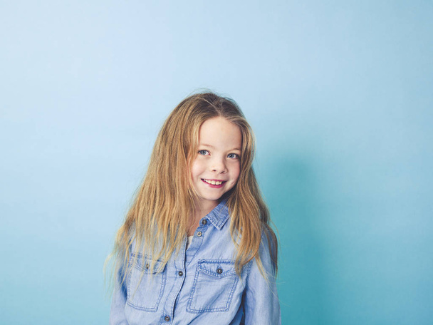 portrait of happy girl in casual clothes looking at camera on pastel blue background    - Zdjęcie, obraz