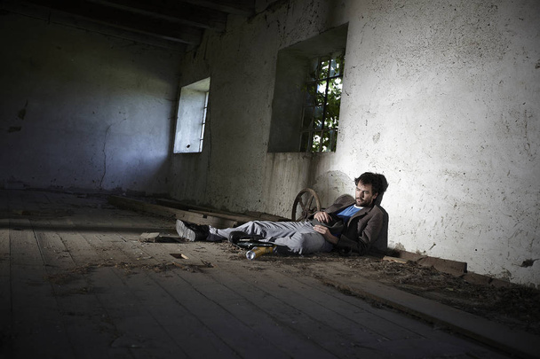 koldus ember piszkos ruhákat feküdt a padlón, és alszik elhanyagolt épület  - Fotó, kép
