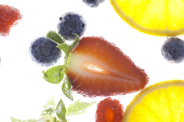  frutti e bacche in acqua su fondo bianco, primo piano
  - Foto, immagini