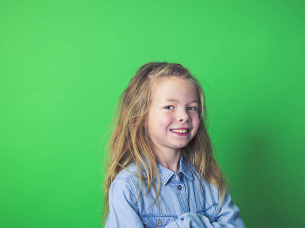 portrait of happy girl in casual clothes looking at camera on green background    - Photo, Image