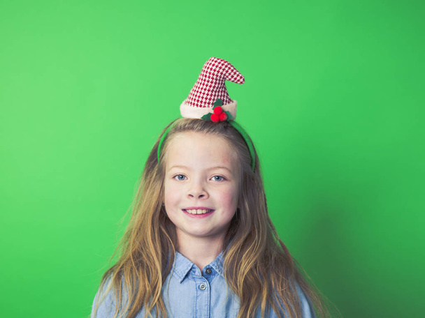portrait of happy girl in Christmas elf hat looking at camera on green background    - Foto, imagen