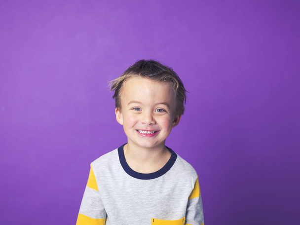 szczęśliwy chłopiec zabawy podczas pozują przed fioletowym tle - Zdjęcie, obraz