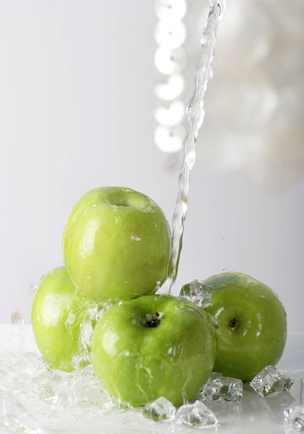 water pouring on pile of green apples, close-up   - 写真・画像