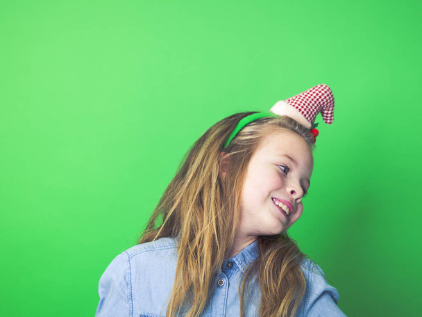 young girl with christmas decoration on head in front of green background - Foto, immagini