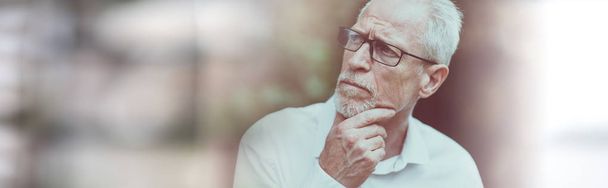Портрет вдумчивого зрелого человека на размытом фоне
 - Фото, изображение