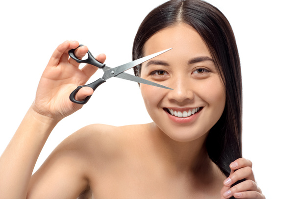 портрет улыбающейся азиатки с ножницами, изолированными на белом, поврежденном волосе и секущихся концах
 - Фото, изображение