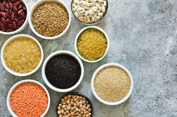 Variación de cereales en cuencos: frijoles, arroz, garbanzos, guisantes sobre un fondo concreto
. - Foto, imagen