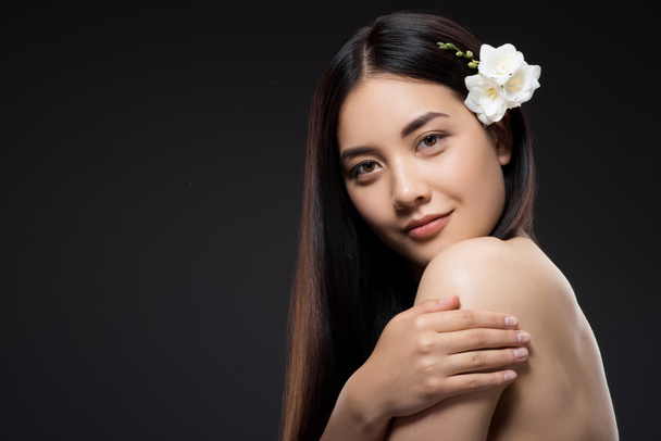 ritratto di bella giovane donna asiatica con fiori bianchi in capelli guardando la fotocamera isolata su nero
 - Foto, immagini