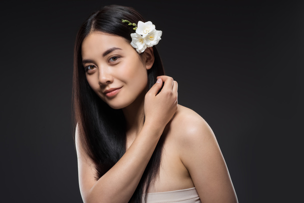 portrait of beautiful young asian woman with white flowers in hair isolated on black - Photo, Image