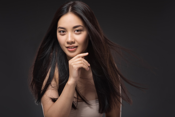 πορτρέτο του νεαρή γυναίκα της Ασίας με όμορφα και υγιή μαλλιά σκούρα βλέπουν φωτογραφική μηχανή που απομονώνονται σε μαύρο - Φωτογραφία, εικόνα