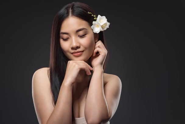 портрет красивой молодой азиатской женщины с белыми цветами в волосах, изолированных на черном
 - Фото, изображение