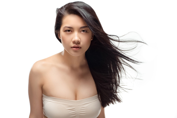 portrét mladé asijské ženy krásné a zdravé vlasy při pohledu kamery izolované na bílém - Fotografie, Obrázek
