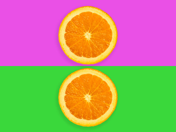 Segmenten van oranje fruit geïsoleerd op kleurrijke paarse en groene pastel achtergrond - frisse moderne minimalistische en creatieve beeld - Foto, afbeelding