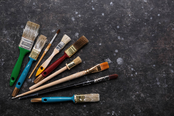 Old grunge paint brushes set on textured dark gray background with copy space. Top view, work tools. - Φωτογραφία, εικόνα