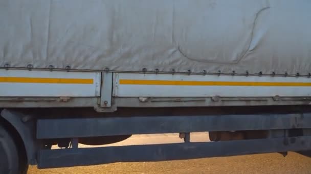 Lorry rides through the countryside with beautiful landscape at background. Wheels of truck ride at asphalt. Truck driving on a highway. Side view Close up Slow motion - Footage, Video