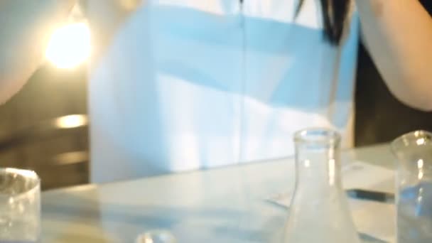 Woman scientist mixing together two liquid substances. Laboratory examination. - Materiał filmowy, wideo