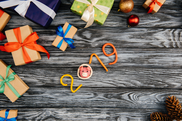верхний вид символа 2019 года и рождественские подарки на деревянной поверхности
 - Фото, изображение