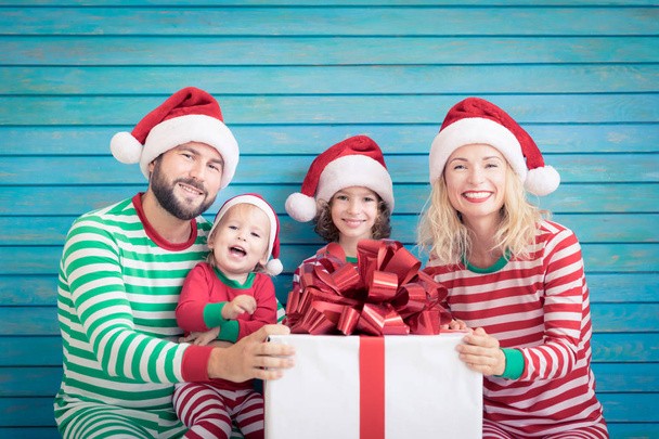 Счастливая семья веселится на Рождество. Отец, мать и дети дома. Рождественский праздник
 - Фото, изображение