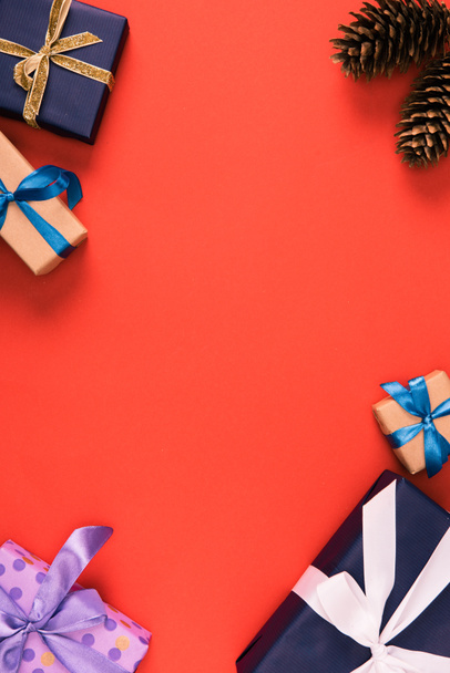 верхний вид рождественских подарков и шишек на красном фоне
 - Фото, изображение