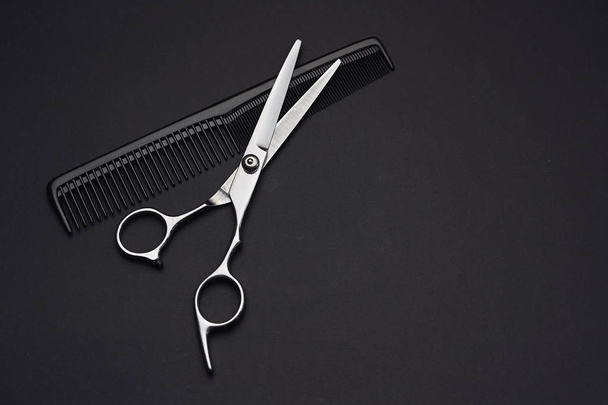 Hairdressers scissors and comb on black background - Photo, Image