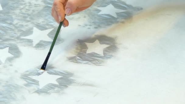 Une main avec des touches soignées rend le coup d'étoiles de peinture argentée
 - Séquence, vidéo