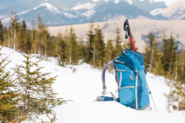 Hátizsák a háttérben hófödte hegyek és a kék ég. A hátizsák a havon. Aktív életmód. Túrázás-a téli időszakban. Berendezések a túrázásra. Trekking botok. - Fotó, kép
