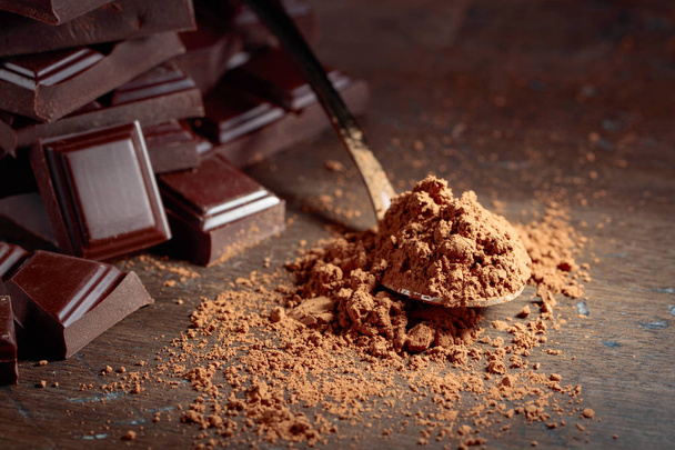 Morceaux de chocolat cassés et poudre de cacao dans une petite cuillère sur un fond en bois. Espace de copie
. - Photo, image