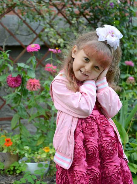 Portrait of the little cheerful girl in a garden - Photo, image