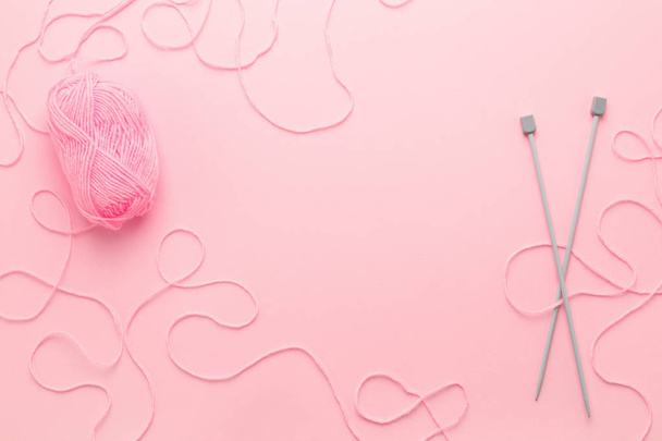 Esquisse de fil rose, aiguilles à tricoter et cadre de fil de laine emmêlé sur la table rose. Concept de vue de dessus, de passe-temps ou de couture
. - Photo, image