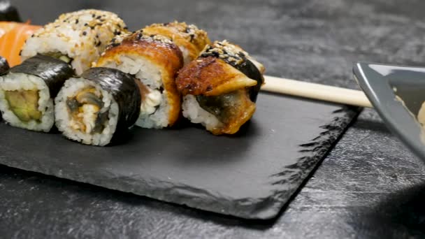 Panecillos de sushi saludables, deliciosos y tradicionales en plato negro
 - Metraje, vídeo