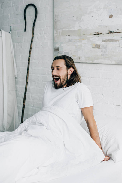 handsome Jesus yawning in bed during morning time at home  - Φωτογραφία, εικόνα