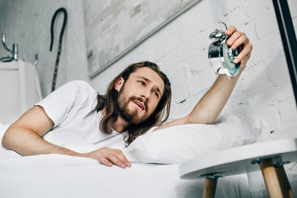 Selektive Fokussierung des Jesus auf das Ausschalten des Weckers im heimischen Bett  - Foto, Bild