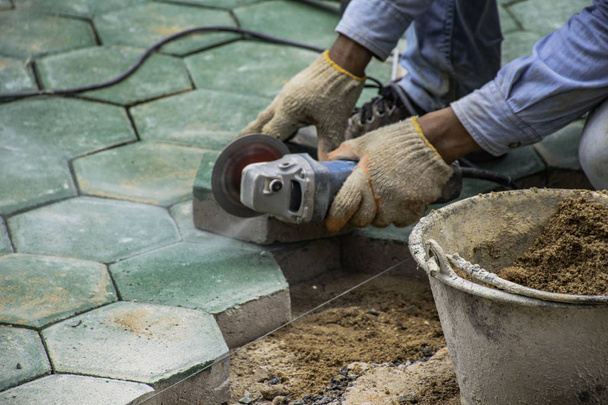 Työntekijät leikkaamalla vihreä betoni kuusikulmainen lohkojen päällystämiseen
. - Valokuva, kuva