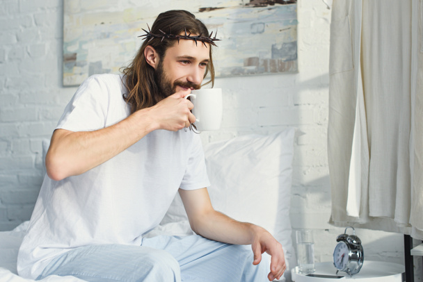 enfoque selectivo de Jesús en la corona de espinas beber café en el dormitorio durante la mañana en casa
 - Foto, Imagen
