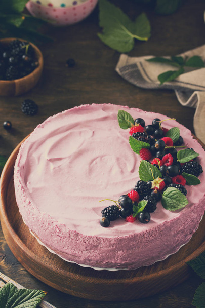 Cake with Black Currant Cream Souffle and Biscuit on a table in a rustic style. Copy space. Toned image. - Photo, Image