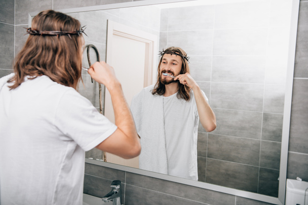 rear view of Jesus with towel over shoulder brushing teeth in bathroom  - Foto, immagini