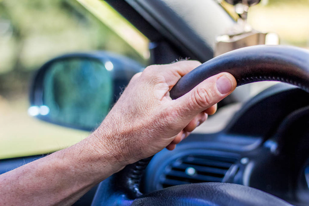 Του ανθρώπου χέρι στο τιμόνι ενός αυτοκινήτου. Οδήγηση στο δρόμο - Φωτογραφία, εικόνα