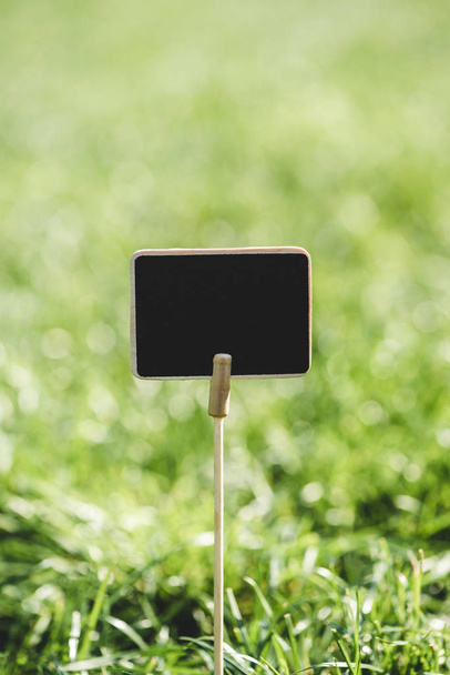 empty wooden blackboard on stick in green grass - Φωτογραφία, εικόνα